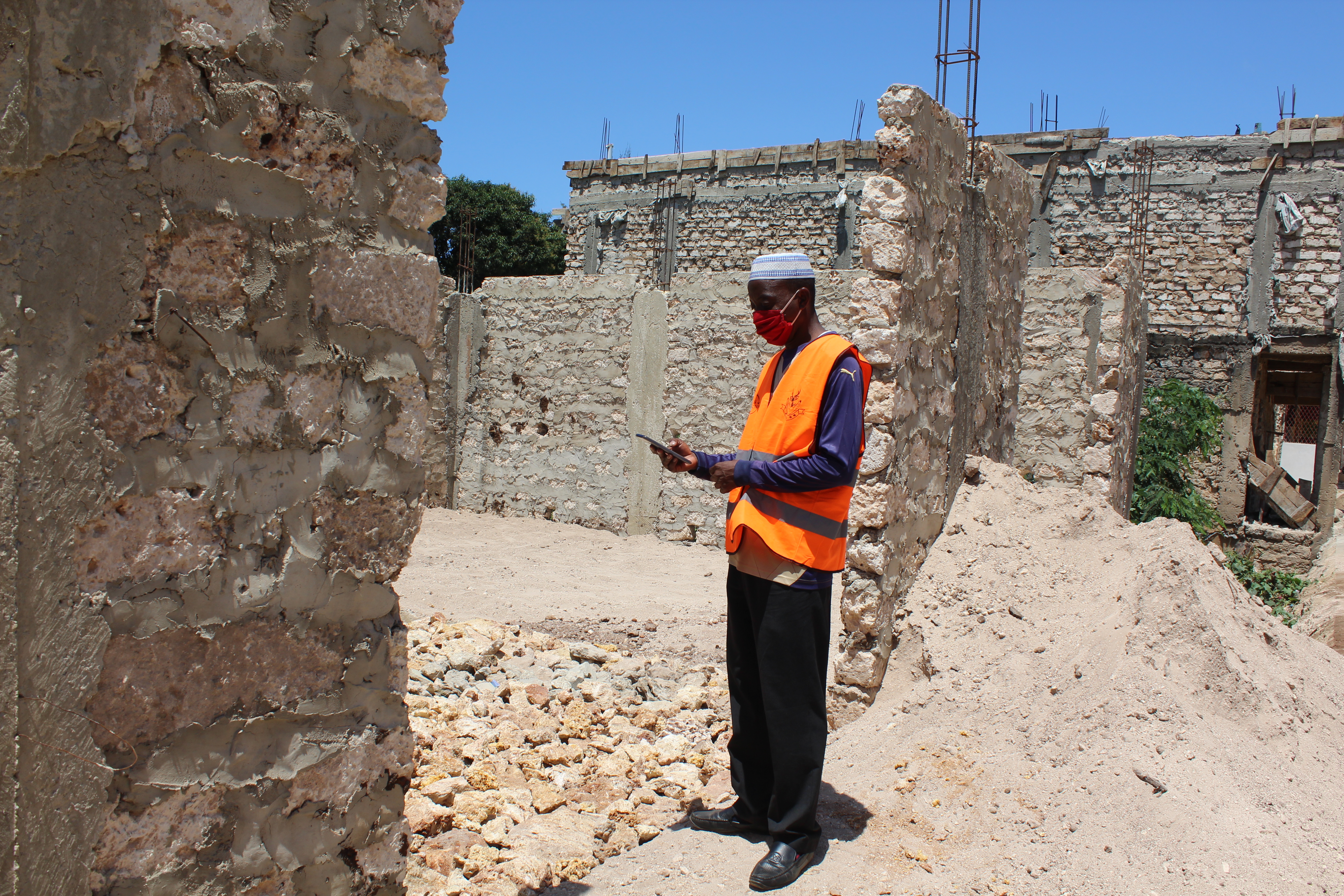 Community monitor wearing PPE and checking that construction is continuing in accordance with plans